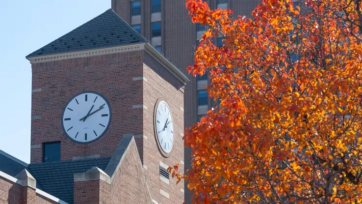 Moody Bible Institute's clocktower with a red and orange-leafed tree in the foreground