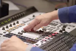 A person adjusting a slider on the sound and media board 