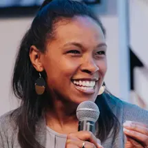 A smiling woman speaking into a microphone