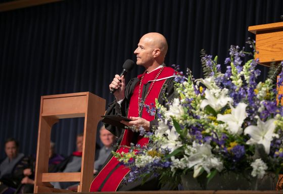 Moody Bible Institute president Mark Jobe kneeling during his inaugural address