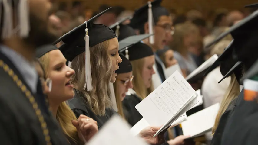 Students singing in graduation regalia.