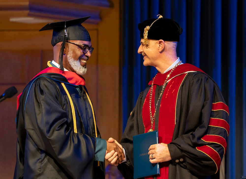 A Master's student shakes hands with President Jobe as he receives his diploma